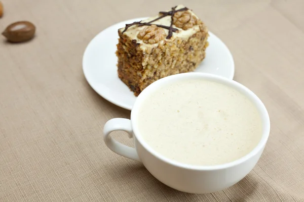 Чашка капучино, кусок торта с орехами, лежащими на тарелке — стоковое фото