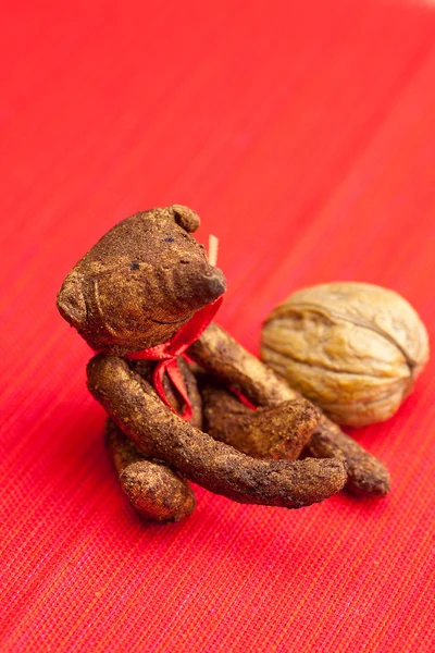 Urso de pelúcia feito à mão e nozes em um fundo vermelho — Fotografia de Stock