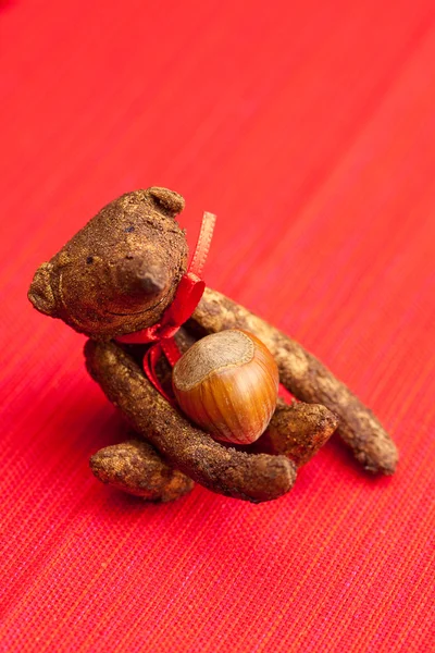 Urso de pelúcia feito à mão e nozes em um fundo vermelho — Fotografia de Stock