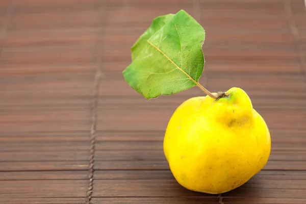 Yellow quinces with a green leaf on a bamboo mat — Stock Photo, Image