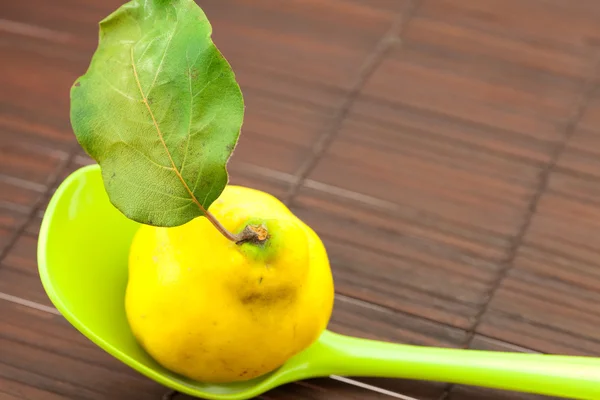 Gelbe Quitten mit grünem Blatt in einem Löffel auf einer Bambusmatte — Stockfoto