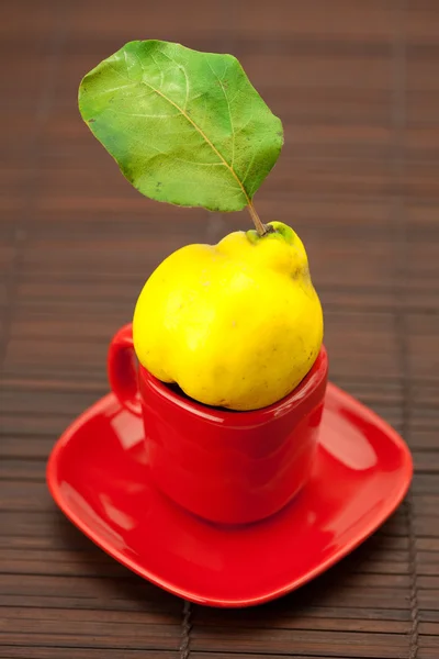 竹マットの上のカップの緑の葉と黄色のマルメロ — ストック写真