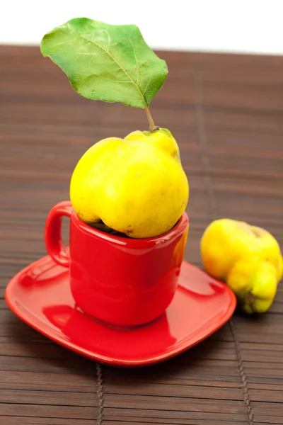 竹マットの上のカップの緑の葉と黄色のマルメロ — ストック写真
