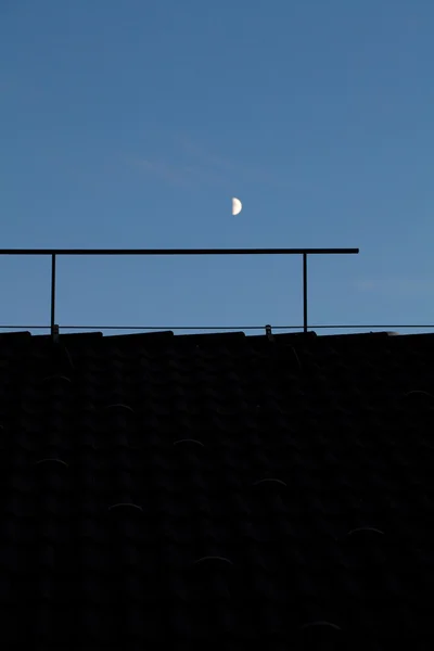 Księżyc na nocnym niebie ponad dach — Zdjęcie stockowe