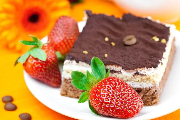 Gerbera, tårta och jordgubbar liggande på orange tyg — Stockfoto