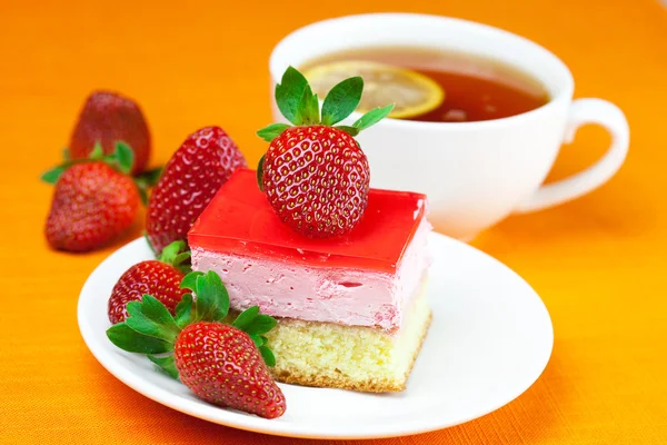 Citroenthee, cake en aardbeien op de oranje stof — Stockfoto