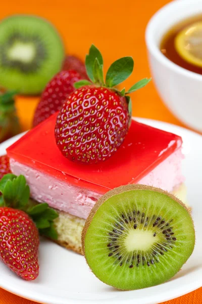Lemon tea, kiwi,cake and strawberries lying on the orange fabric — Stock Photo, Image