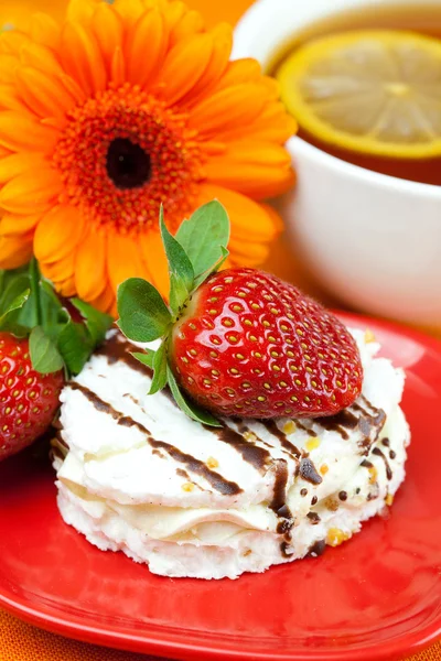 Citroenthee, gerbera, cake en aardbeien liggend op de oranje fabr — Stockfoto