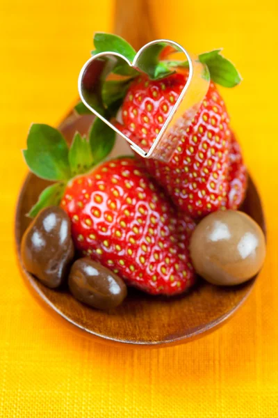 Strawberry, hearts and chocolate candy in the wooden spoon of th — Stock Photo, Image
