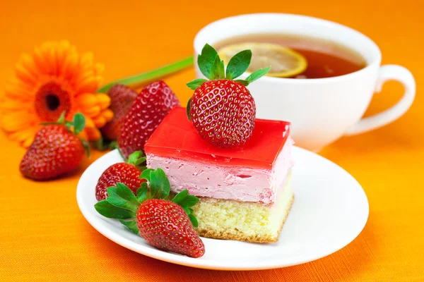 Gerbera, thé au citron, gâteau et fraises sur la fa orange — Photo