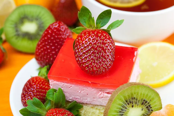 Thé au citron, kiwi, gâteau et fraises couchés sur le tissu orange — Photo