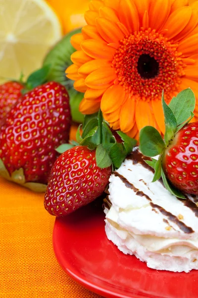 Citroen, gerbera, cake en aardbeien liggend op het oranje weefsel — Stockfoto