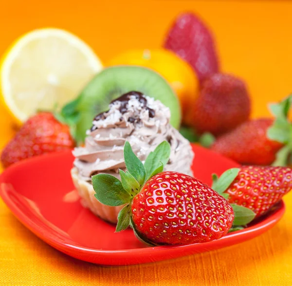 Zitrone, Mandarine, Kiwi, Kuchen und Erdbeeren liegen auf dem orangefarbenen Tisch — Stockfoto