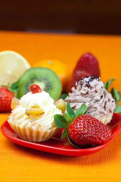 Lemon,mandarin,kiwi,cake and strawberries lying on the orange fa — Stock Photo, Image