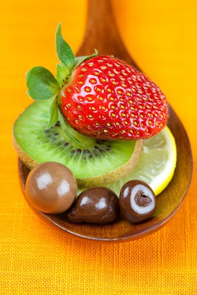 Strawberries, kiwi and chocolate candy in the wooden spoon of th — Stock Photo, Image