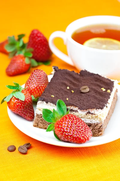 Lemon tea, cake and strawberries lying on the orange fabric — Stock Photo, Image