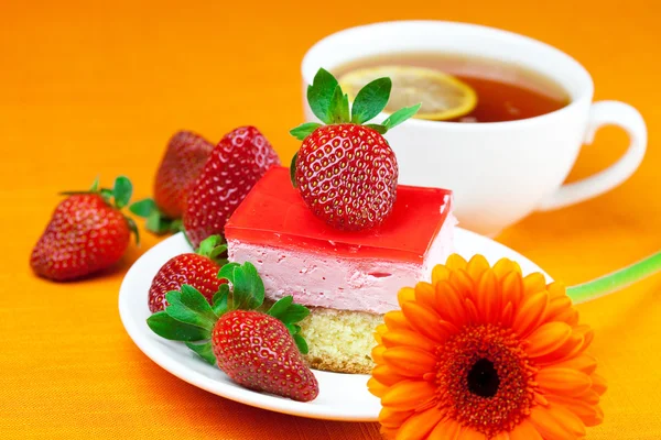 非洲菊、 柠檬绿茶、 蛋糕和草莓躺在橙色 fa — 图库照片