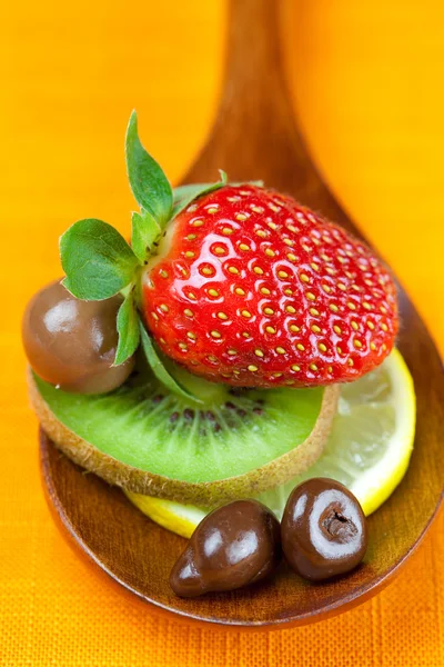 Strawberries, kiwi and chocolate candy in the wooden spoon of th — Stock Photo, Image