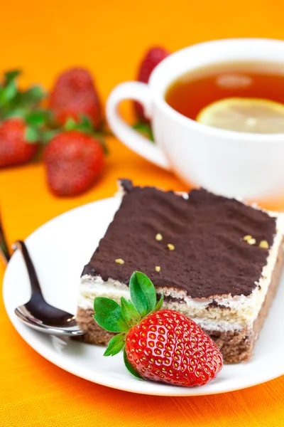 Lemon tea, cake and strawberries lying on the orange fabric — Stock Photo, Image