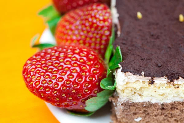 Gâteau sur une assiette et fraises couchées sur le tissu orange — Photo