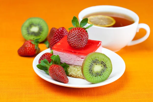 Citroenthee, kiwi, taart en aardbeien liggend op het oranje weefsel — Stockfoto