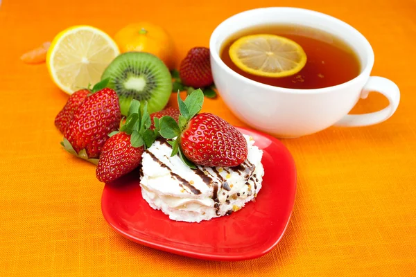 Chá de limão, limão, tangerina, quivi, bolo e morangos deitados em t — Fotografia de Stock