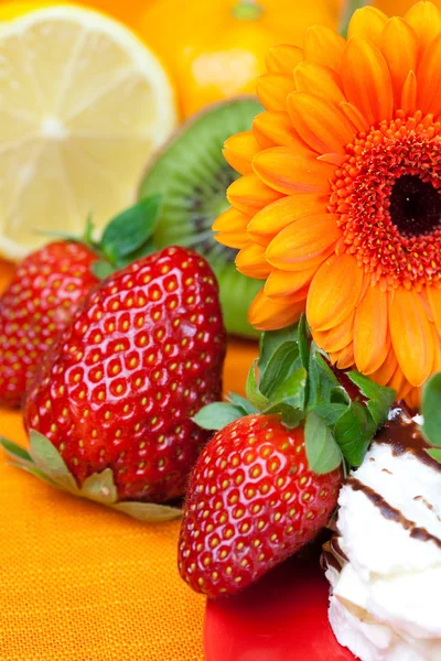 Λεμόνι, ζέρμπερες, κέικ και φράουλες που βρίσκεται στο πορτοκαλί ύφασμα — Φωτογραφία Αρχείου