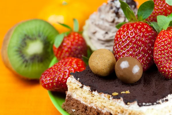 Pastel, caramelos de chocolate, mandarina, kiwi y fresas en el o —  Fotos de Stock