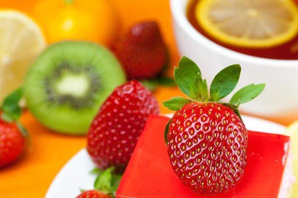 Citronte, kiwi, tårta och jordgubbar liggande på orange tyg — Stockfoto