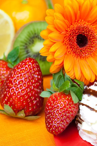 Citron, gerbera, gâteau et fraises couchés sur le tissu orange — Photo