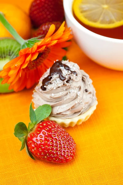 Gerbera,lemon tea,mandarin,kiwi,cake and strawberries lying on t — Stock Photo, Image