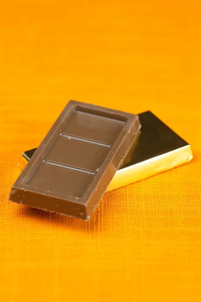 Chocolate bars wrapped in the orange fabric — Stock Photo, Image
