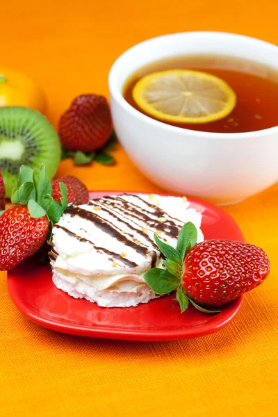 Лимонный чай, киви, торт и клубника лежат на оранжевой ткани — стоковое фото