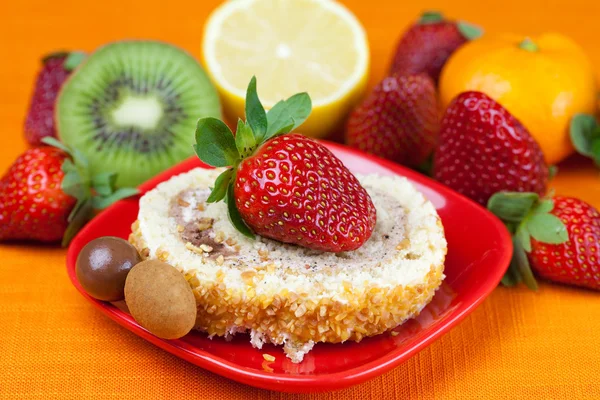 Kuchen, Kiwi, Zitrone, Mandarine und Erdbeeren liegen auf dem orangefarbenen Tisch — Stockfoto