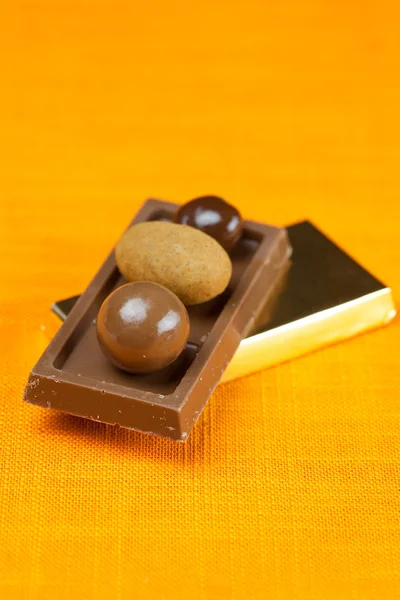 Chocoladerepen en snoep op de oranje stof — Stockfoto