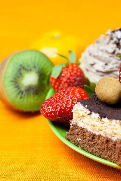 Cake, chocolade snoep, tangerine, kiwi en aardbeien op de o — Stockfoto
