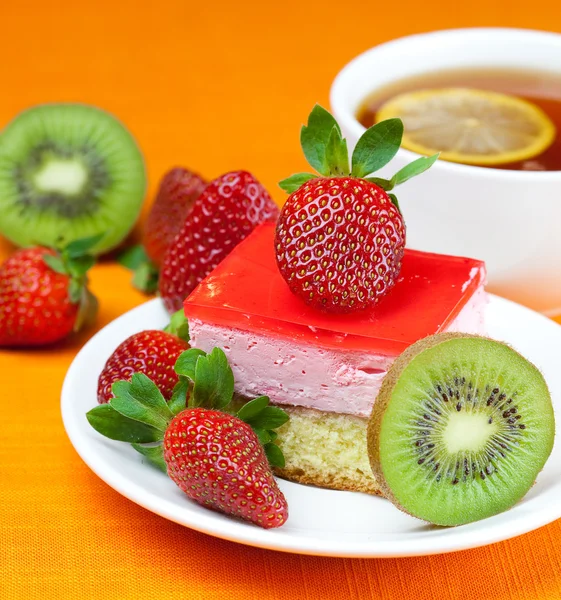 Ceai de lămâie, kiwi, tort și căpșuni întinse pe țesătura portocalie — Fotografie, imagine de stoc