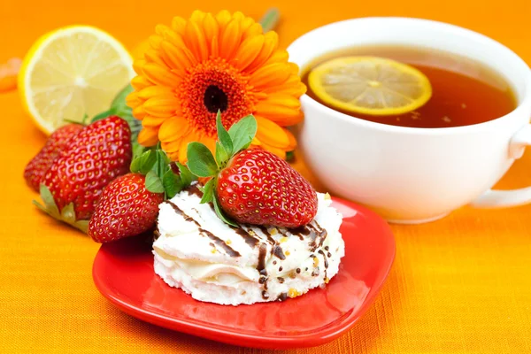 Лимонный чай, лимон, гербера, торт и клубника лежат на оране — стоковое фото