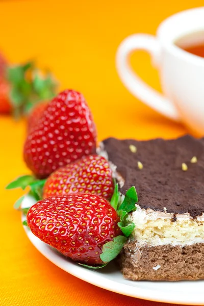 Thé au citron, gâteau et fraises couchés sur le tissu orange — Photo