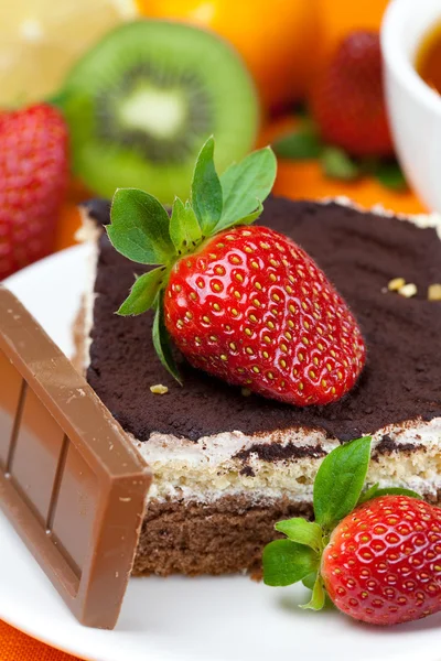 Lemon tea,chocolate, kiwi,cake and strawberries lying on the ora — Stock Photo, Image