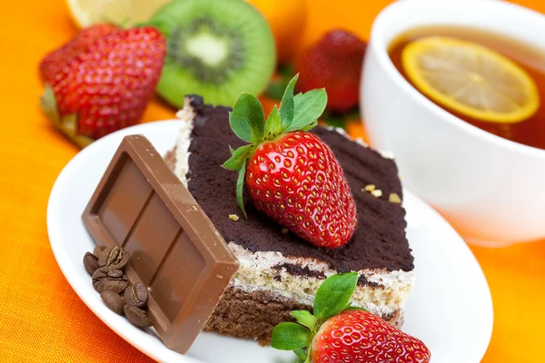 Zitronentee, Schokolade, Kiwi, Kuchen und Erdbeeren auf dem Boden liegend — Stockfoto