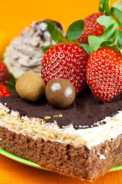 Ciasto, czekoladki i truskawki na pomarańczowym tkaniny — Zdjęcie stockowe