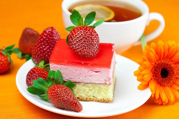 Gerbera, thé au citron, gâteau et fraises sur la fa orange — Photo