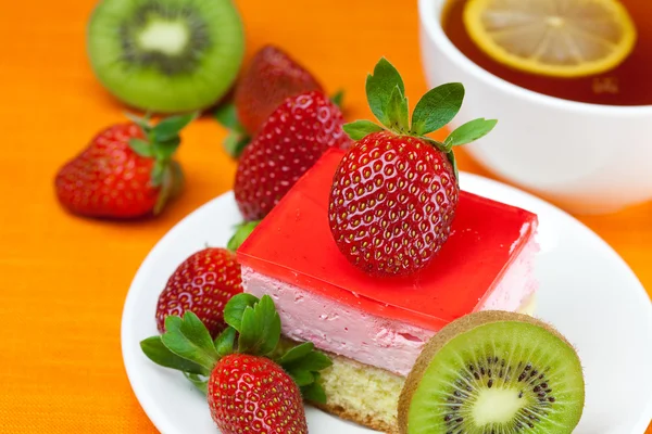 Té de limón, kiwi, tarta y fresas que yacen sobre la tela naranja — Foto de Stock