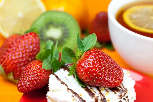 Lemon tea,lemon, mandarin, kiwi,cake and strawberries lying on t — Stock Photo, Image