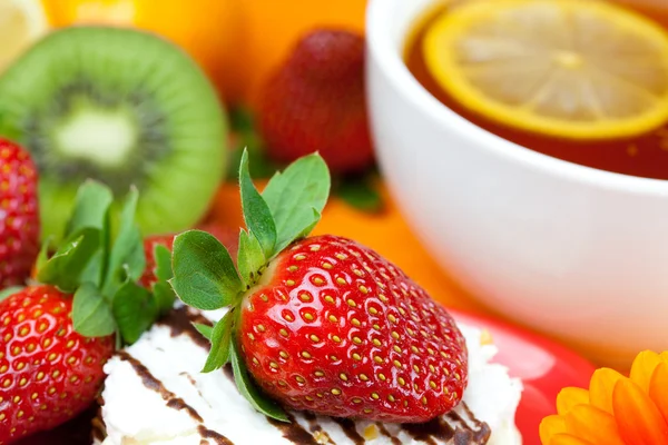 Lemon tea, mandarin, kiwi,cake and strawberries lying on the ora — Stock Photo, Image