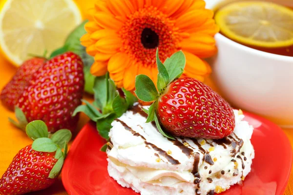 Thé au citron, citron, gerbera, gâteau et fraises couchés sur l'oran — Photo