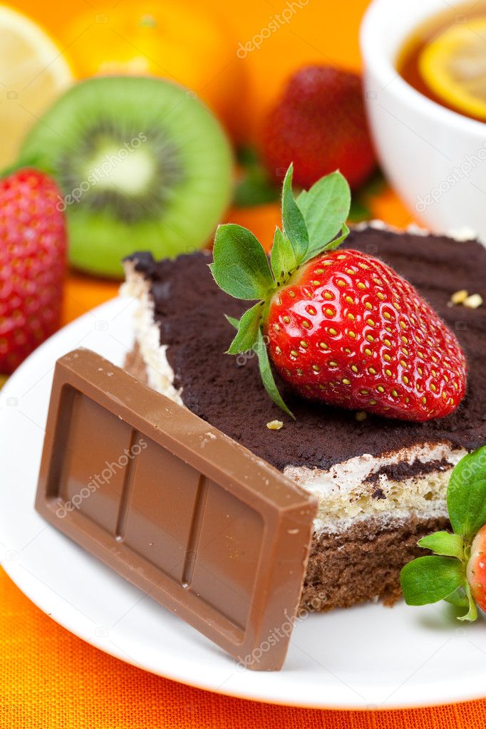 Lemon tea,chocolate, kiwi,cake and strawberries lying on the ora