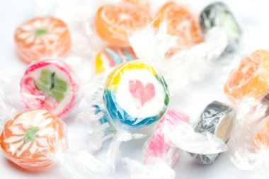 Background of multi-colored candies in shiny wrappers clipart