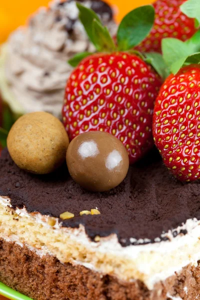 Cake, chocolade en de aardbeien op de oranje stof — Stockfoto